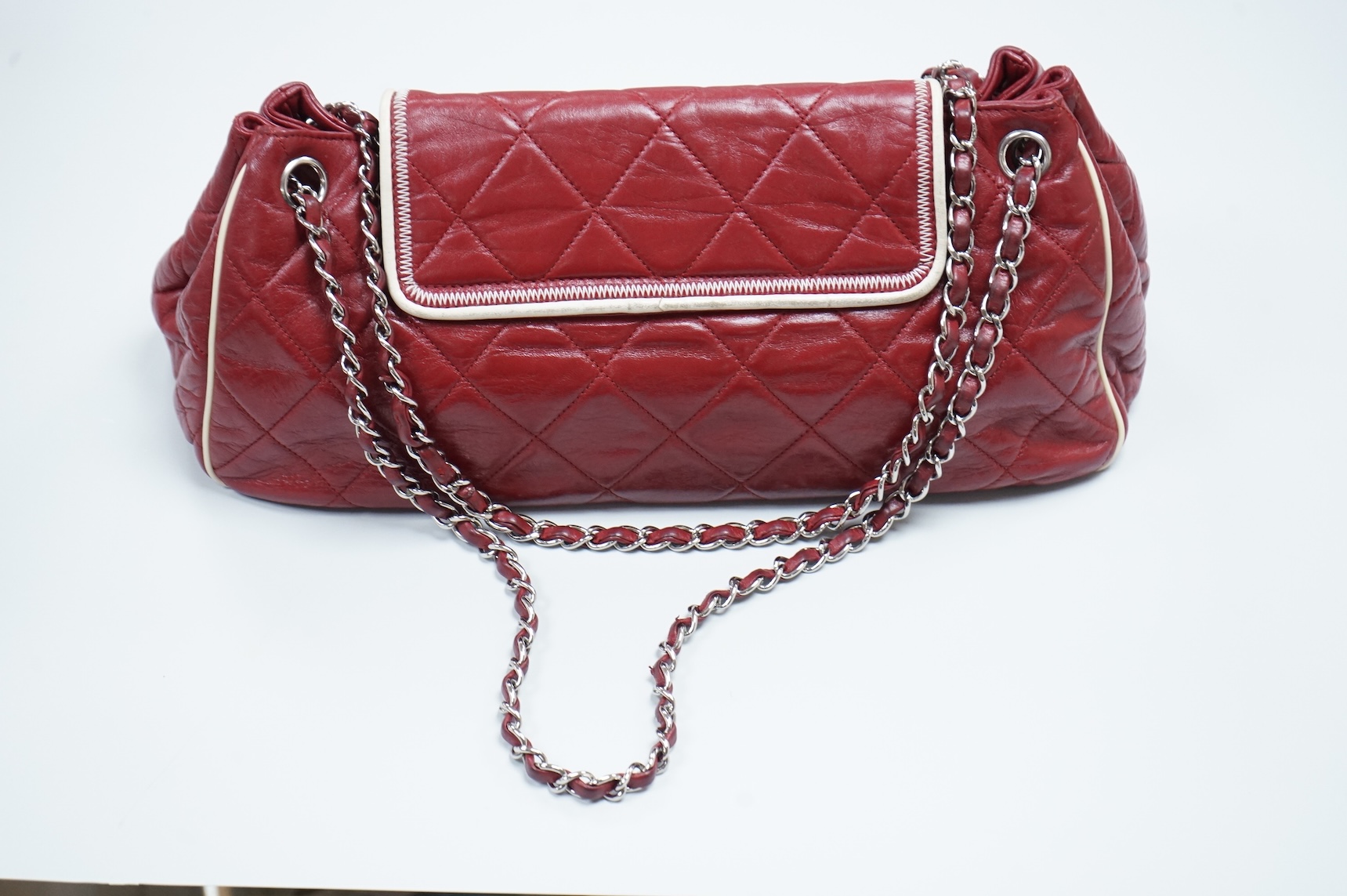 A Chanel East West dark red quilted leather flap shoulder bag with silver hardware, date code 12115484, with original receipt, dust cover and box, 35cm wide, Provenance: purchased by the vendor in Selfridges